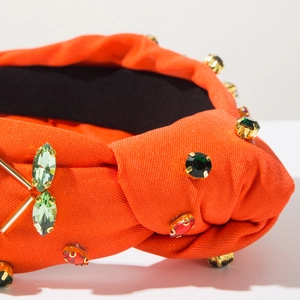 Dettaglio cerchietto arancione con nodo in seta e borchie con strass in cristallo colorati