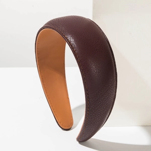 Close-up of a wide dark brown leather headband with lychee grain and contrast stitching