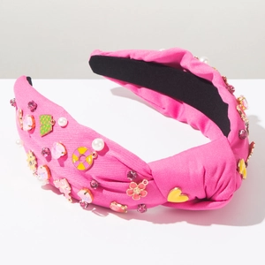 Detalle de diadema de tela rosa con nudo, perlas, cristales de corazón y flores de esmalte