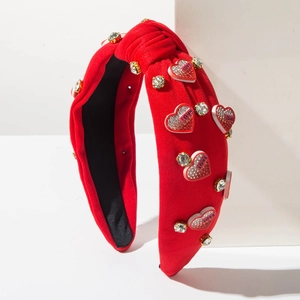 Dettaglio del cerchietto rosso a coste con nodo, cuori decorativi e strass lucidi