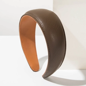 Close-up of brown leather wide headband with lychee pattern texture and fine stitching
