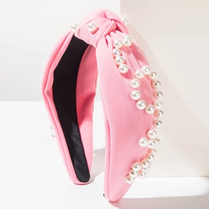 Vue détaillée d'un serre-tête noué rose orné de perles blanches sur tricot doux