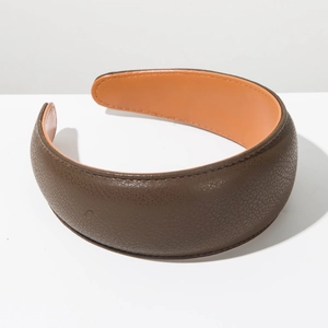 Detailed close-up of wide faux leather headband showing brown texture and orange lining
