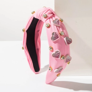 Dettaglio del cerchietto in tessuto rosa con cuori LOVE e strass scintillanti