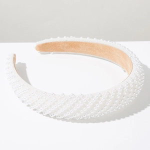 Detailed close-up of handmade white pearls and soft suede lining on a wide luxury headband