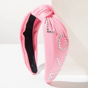 Détail d'un serre-tête rose noué avec lettres LOVE en strass et tissu texturé