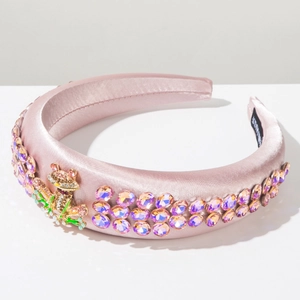 Close-up of pink satin headband with rhinestone frog charm and sparkling purple crystals