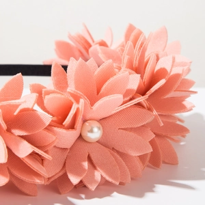 Detailed macro view of handmade 3D coral pink fabric flower headband with pearl center