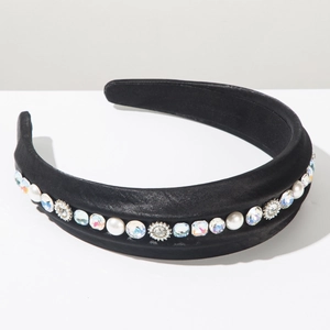 Detailed close-up of thick black satin headband with white pearls and sparkling rhinestones