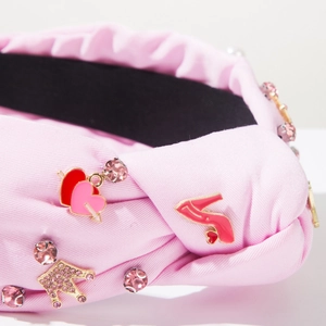 Primer plano de diadema de tela rosa con corona de strass y colgantes de esmalte