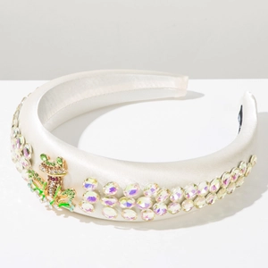 Detailed view of a white padded satin headband with double-row rhinestones and a frog brooch