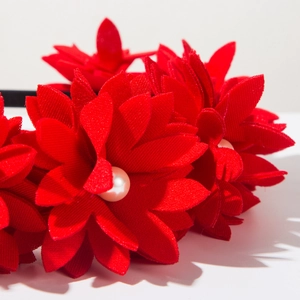 Macro detail of handmade red fabric flower headband with a center faux pearl bead