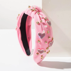 Dettaglio di un cerchietto rosa con nodo decorato con strass, cuori e perline