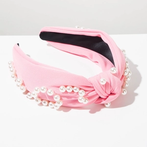 Détail du serre-tête noué rose avec perles blanches et texture en tricot doux