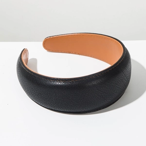 Detailed view of the wide leather headband with black litchi grain and orange lining