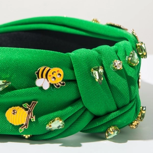 Detailansicht eines grünen Knotenstirnbands mit Kristallbienen und Emaille-Details