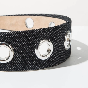 Detailed close-up of black denim headband texture with silver metal eyelets