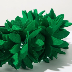 Detailed macro view of green fabric flower headband with a grey pearl center accent