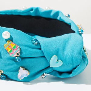 Detalle de diadema de tela azul con pedrería de corazón y adornos de perlas blancas