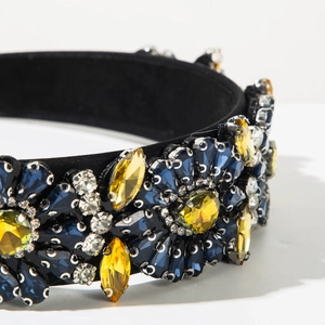 Détail du serre-tête baroque serti de pierres bleues et jaunes sur satin noir