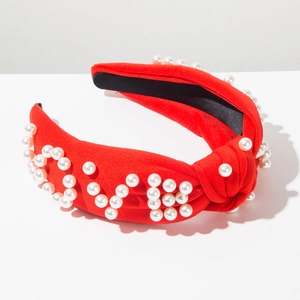 Détail du serre-tête noué rouge orné de perles blanches formant le mot LOVE