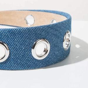 Close-up of denim headband featuring textured fabric and polished silver metal eyelets