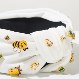 Detailansicht eines weißen Stoff-Haarreifens mit Strasssteinen und Bienen-Dekor