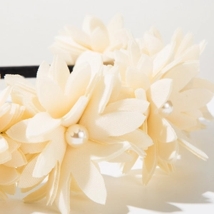 Detail of white fabric flowers with pearl centers on a stylish handmade headband