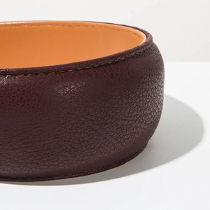 Detailed macro view of dark brown lychee grain leather and orange lining stitching