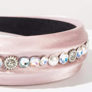 Close-up of pink satin headband with elegant crystals and white pearls detail