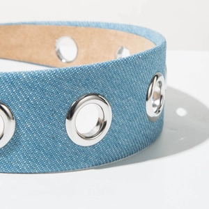 Macro shot of light blue denim fabric headband with silver eyelets and texture