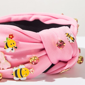 Nahaufnahme des rosa Stoffstirnbands mit Emaille-Bienen, Strass und Schleifen