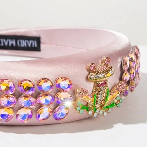 Detail of pink satin headband featuring sparkling rhinestones and a jeweled frog charm