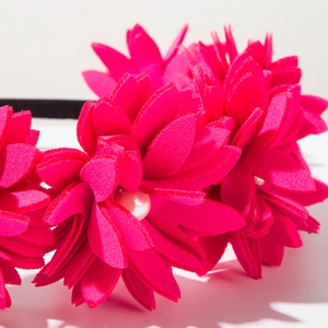 Close-up of pink fabric 3D flower headband with elegant pearl center and black base