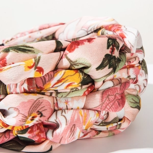 Close-up of pink floral fabric headband featuring a braided wide-brim design and textures
