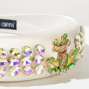 Detail of white satin headband with crystal rhinestones and luxury jeweled frog ornament
