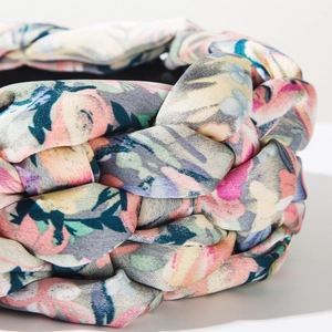Detailed macro view of multi-strand braided floral fabric headband with silk-like texture
