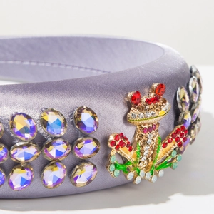 Detail of lilac satin headband with sparkling rhinestones and a jeweled frog accent