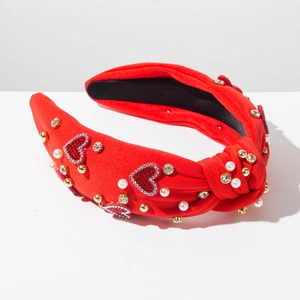 Dettaglio fascia rossa annodata con cuori di paillettes, perle bianche e strass dorati