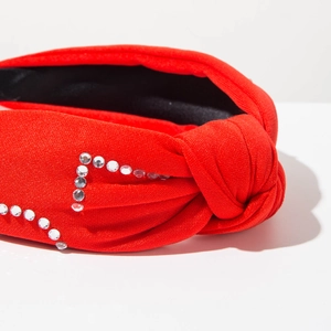 Détail d'un serre-tête noué rouge orné de strass blancs brillants sur tissu