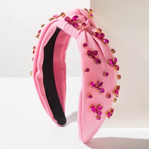 Dettaglio di una fascia annodata rosa con strass a forma di cuore e montatura dorata