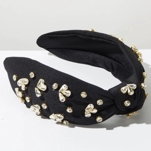 Dettaglio del cerchietto in raso nero con cuori di strass e castone dorato a griffe