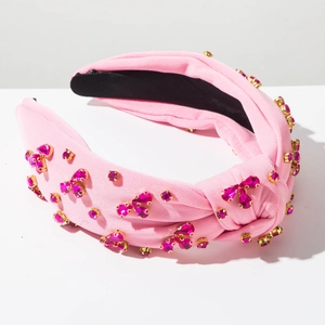 Dettaglio di un cerchietto rosa annodato con strass scintillanti e fodera nera
