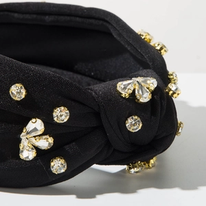 Dettaglio ravvicinato del nodo su fascia per capelli in tessuto nero con strass e cristalli
