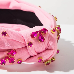 Dettaglio fascia rosa annodata con strass scintillanti a goccia e trama a costine