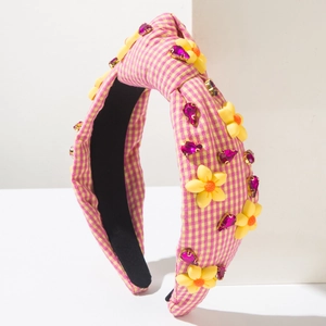 Gros plan du serre-tête à carreaux jaunes avec fleurs en tissu et strass brillants