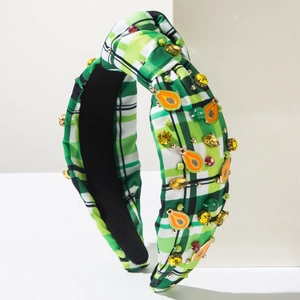 Detail of green plaid headband with yellow rhinestones and orange fruit accents
