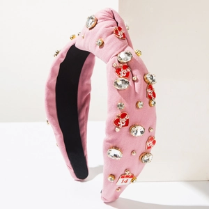 Detail of pink knotted headband with heart Love charms, rhinestones and February 14 tag