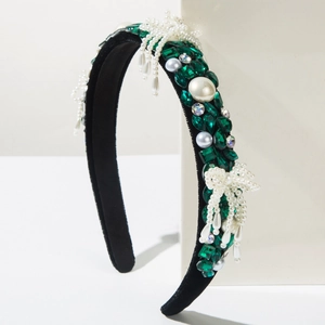 Detailed view of Baroque velvet headband with emerald crystals and pearl bow detail