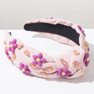 Détail d'un bandeau en tissu avec des fleurs mauves et des cristaux roses élégants